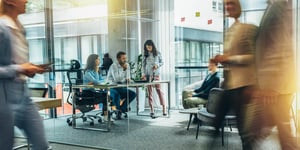 Professionals collaborating in an office with glass walls.